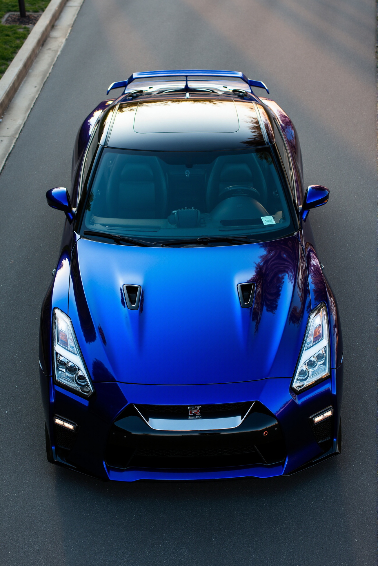 <lora:Nissan_GT-R_R35:0.7>  A slightly from above of a gorgeous Nissan GT-R R35 in all its shining glory. In a style of clean look. The car has black paint job with dark blue undertone. Mirror-like, high gloss finish catches bright highlights. Vibrant color palette.