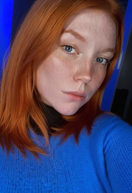 fair skin with freckles, long straight orange hair with a reddish tint, straight hairstyle, cool artificial lighting, wearing a bright blue knit sweater, bright blue eyes, medium-length brown hair, wearing a black high-neck sweater, neutral expression with a hint of contemplation.