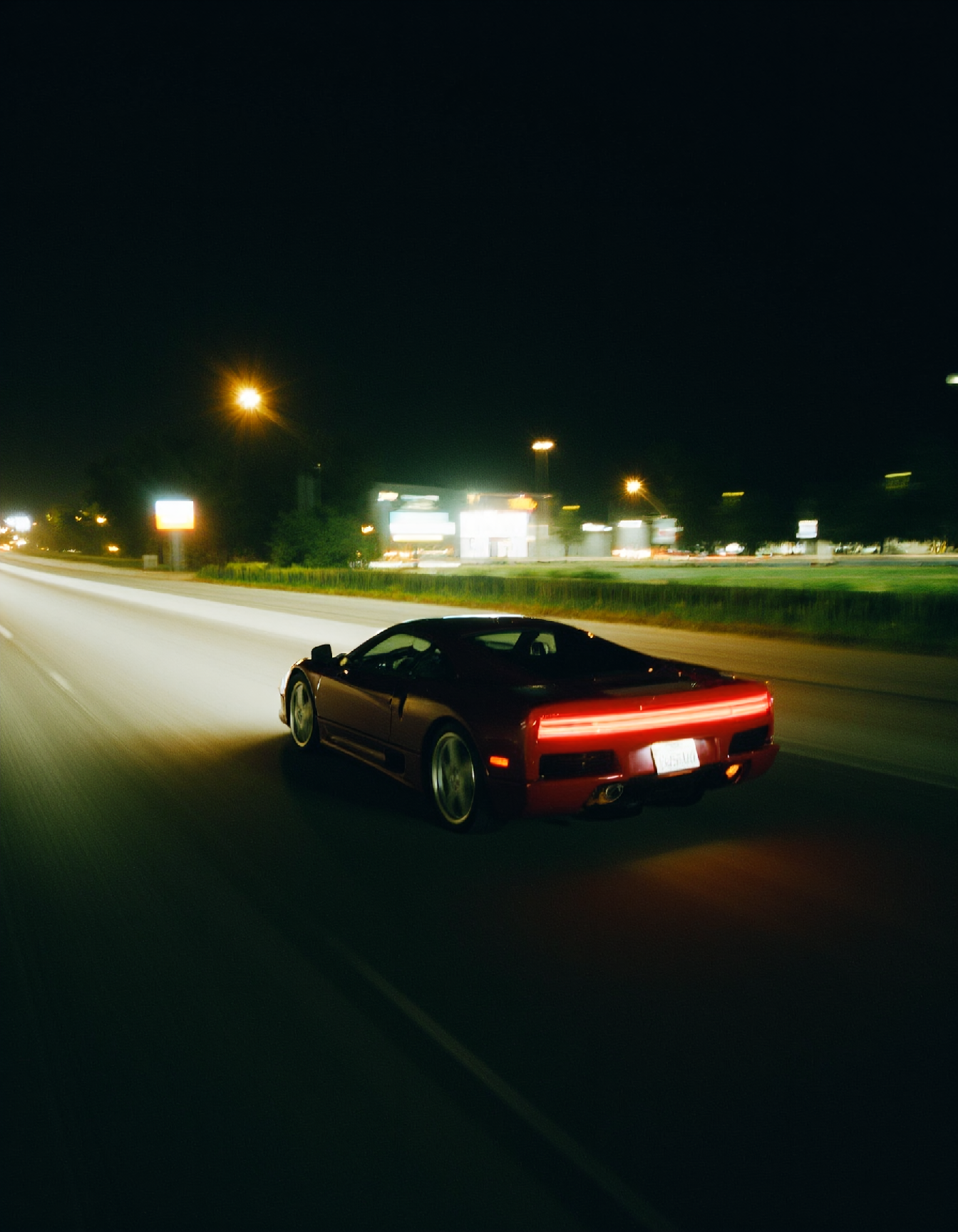 Kodak cinematic film style, professional photo of a sleek sports car speeding on a highway at night, motion blur, film grain, bokeh