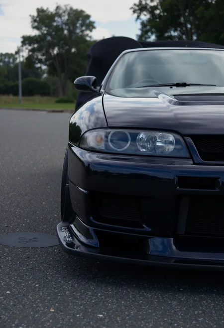 <lora:Nissan_Skyline_GT-R_R33:0.8> A slightly from a side of a modified Nissan Skyline GT-R R33 in all its shining glory. Mirror-like, glossy finish.