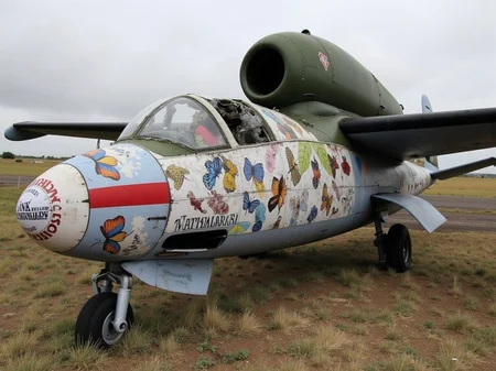 <lora:heinkel-he-162-salamander-flux-d:2.3> A decaying heinkel He 162 salamander wrapped in silk banners covered in butterfly patterns and pilot names, its canopy shattered like stained glass. The entire image is framed like a heavy-metal album cover, surreal and melancholic.