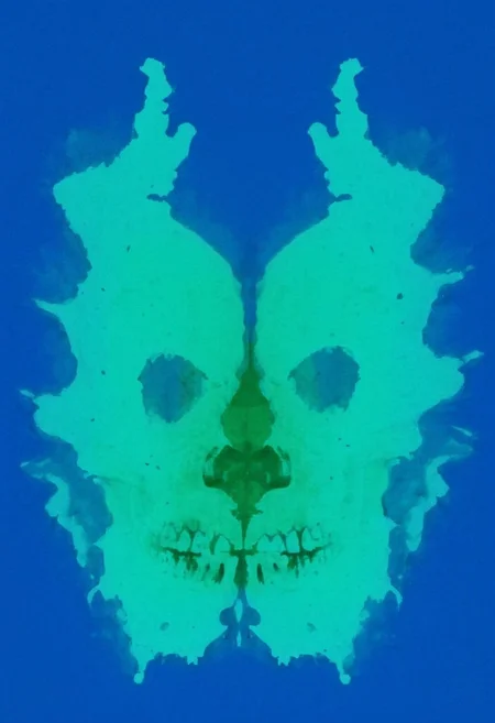 A rorschach-test resembling two symmetrical skulls, dark Blue/green translucent ink splashes