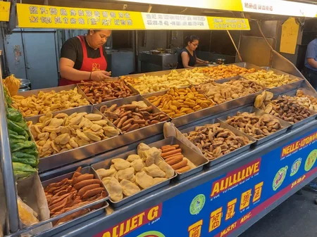 buffet,A street food , set up along a bustling sidewalk. She is actively preparing or serving food, her appearance reflecting both professionalism and beauty. The colorful and inviting stall displays a variety of local delicacies. Steam or smoke rises from the cooking equipment, adding to the ambiance. The background captures the lively street scene with pedestrians showing interest in the food. The scene should be as realistic as a high-resolution photograph, with natural lighting that highlights the vibrant colors and textures of the food, the authenticity of the street setting, and the allure of the vendor, <lora:t9m:0.75>,night market,