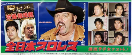 An old, beat-up, torn, and ripped Japanese wrestling poster from the 1990s with big red Japanese characters along the bottom representing "ZEN NIHON PURORESU". The event is titled "Giant Series" and it features age 45 burly mustached cowboy Stan Hansen in a cowboy hat and a suede fringed vest spitting tiny juicy dark brown strands of chewing tobacco from his yelling mouth. Nine other wrestlers are presented in a grid around him. The background is blue with a green stripe.