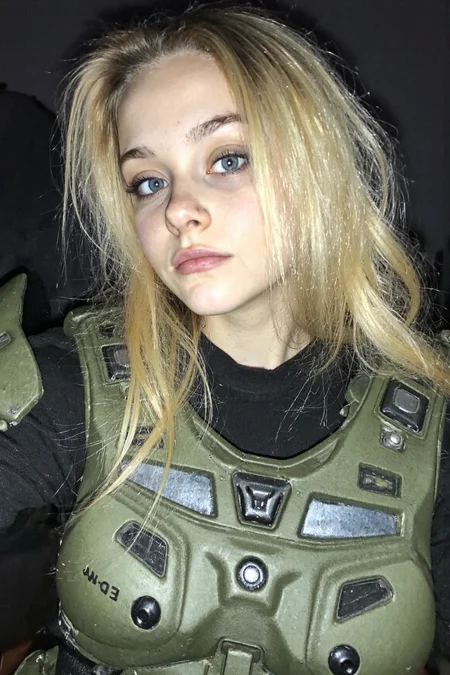 s2ms8ng, young woman wear Master Chief's armor with no helmet, early 20s, masterchief, looking at the viewer, amateur quality, low light, underexposed, partially shadowed face, long blonde haircut, blue eyes, 