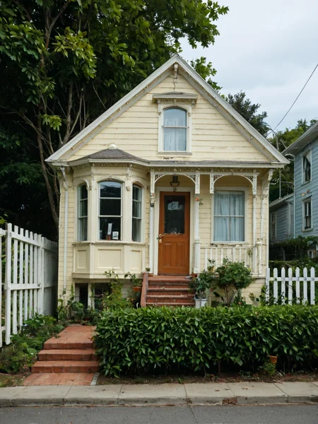 score_9,score_8_up,score_7_up, (v1ct0r14n:1), arched windows, bay windows, transom, small cornice, clapboard siding ,trim, ornate molding, columns on portico,  human scale, whole house in frame, tree,  power lines, telephone lines, car parked in front, circa 2025, fence, bushes, front view,  straight on,  short cornice, short architrave, white paint, clapboard siding, 2 floors, house,<lora:Victorian_House_Pony-000008:1>