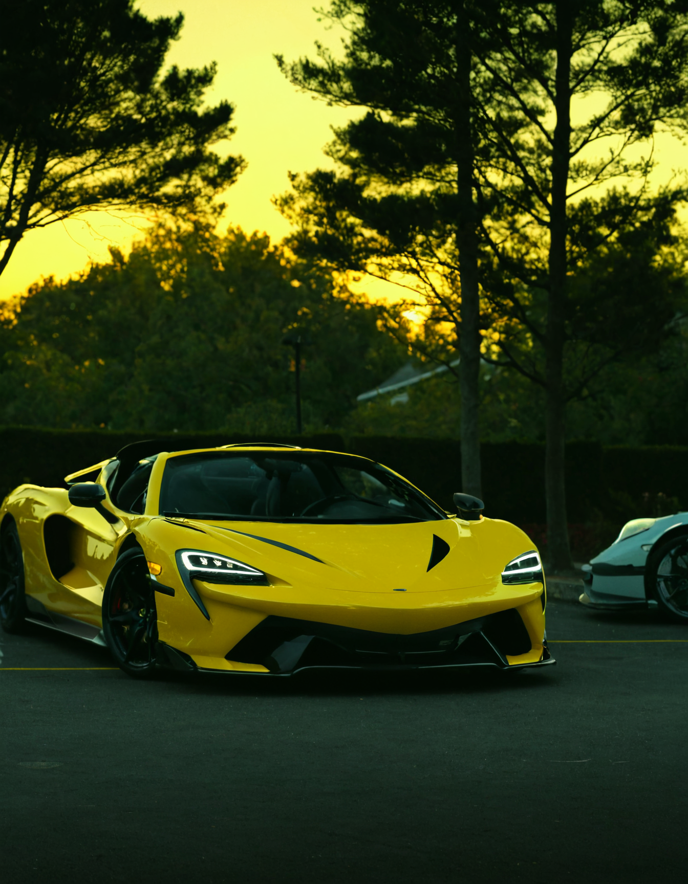 <lora:R0k00M0t0rV3h1c13HD:1>,r0k00m0t0rv3h1c13hd,r0k00bstr0cthd,car,super car,sports car,, two cars parked in a parking lot next to each other with trees in the background and a yellow light shining on the car [2]