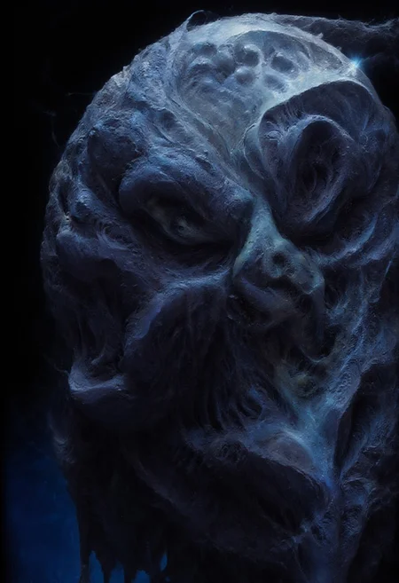 A close-up of a menacing creature's face, rendered in a dark and eerie style. The creature has a pale complexion, deep-set, cracked eyes, and sharp, menacing teeth. The color palette consists of deep blues, blacks, and grays, creating a somber and foreboding atmosphere. A deep blue background contrasts with the creature's pale skin, making it the focal point of the image