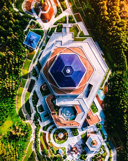 vertical perspective aerial photography, unique_architecture, building, geometric_design, surrounded_by_trees, nature, landscape, <lora:sky:0.8>