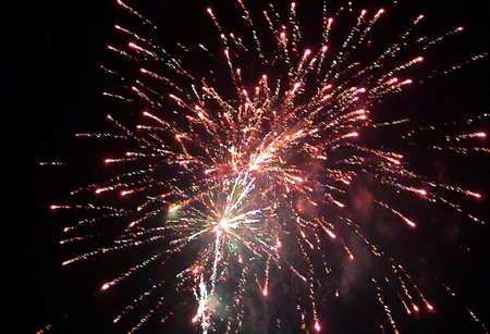 m8vic2, Bright colorful fireworks display, multiple bursts with red, orange, white, and green sparks, night sky background, dense smoke trails, vivid streaks of light radiating outward, outdoor setting, dark atmosphere, overexposed light from fireworks bursts, no visible text or signage, dynamic view upward.,