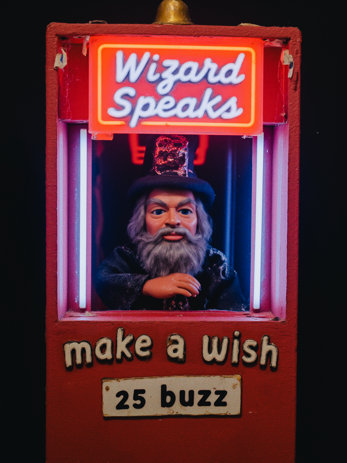 tivoli fortune-telling machine, the automaton machine has a thunderbird puppet wizard whitebeard mannequin inside, neon light sign text reads "Wizard Speaks" and below "Make A Wish: 25 buzz"
