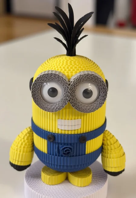 Linguistic: A playful paper sculpture of a Minion where its iconic cylindrical body is crafted from bright yellow papers with precise geometric folds creating its overalls in layered denim-blue papers. The signature goggle is constructed through metallic silver paper rings with transparent paper for the lens, while tiny paper mechanics suggest its adjustable strap. The character's expressions are created through precise paper engineering - from its wide-eyed enthusiasm to its mischievous grin - while wispy black paper strands create its spiky hair,paperarthk,aidmaMJ6.1