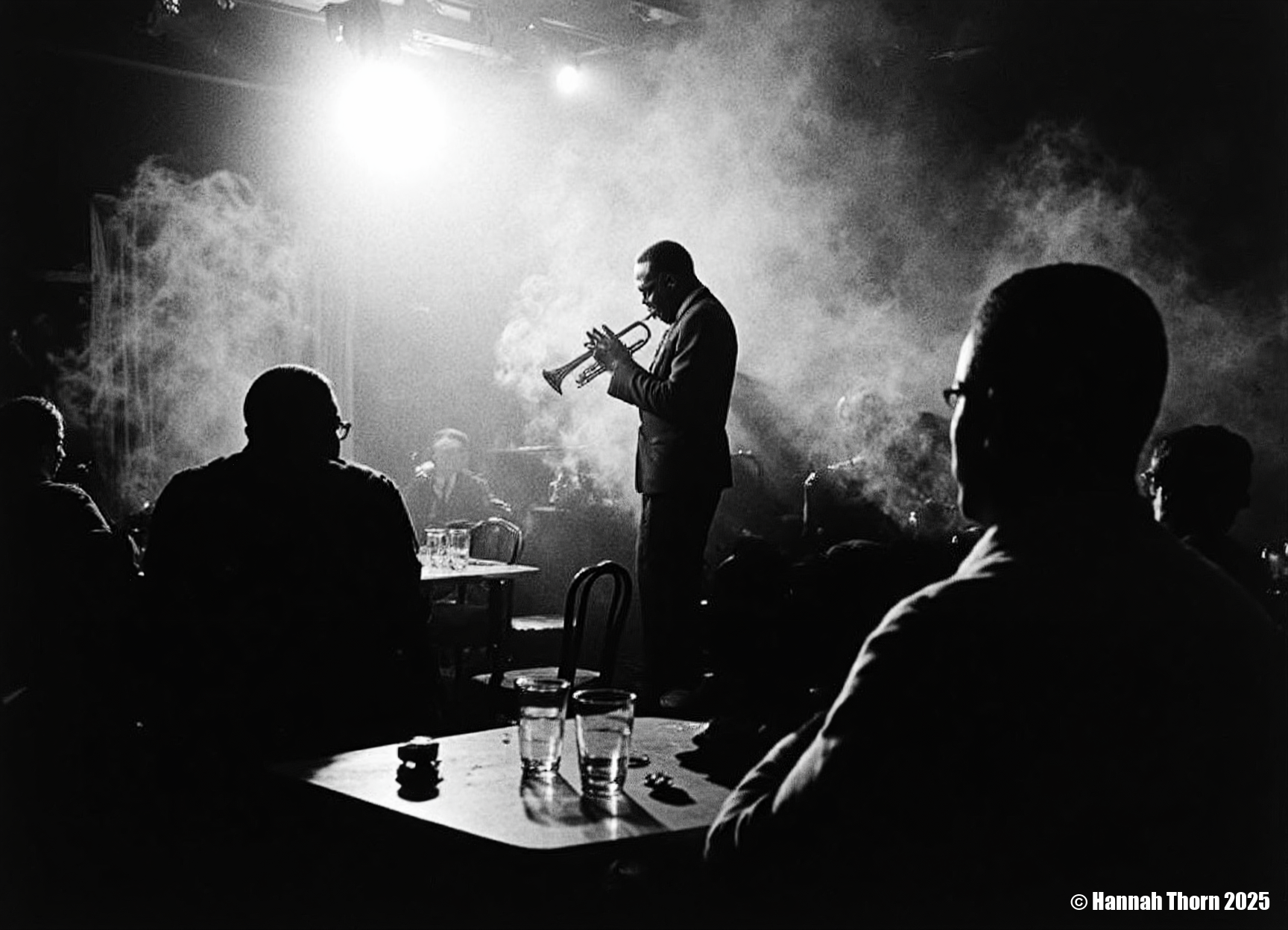 The image is a black and white photograph of Miles Davis playing his trumpet.  The photo is taken in a dimly lit, smoky environment, possibly a jazz club. Davis is centrally positioned, but slightly off-center, his body angled towards the trumpet. He's captured mid-performance, his face partially obscured by shadows and the smoke, creating a dramatic and mysterious atmosphere.  He's wearing a dark suit. His focus is entirely on his instrument.  In the foreground, the backs of other patrons are visible, partially silhouetted, seated at a table with glasses, suggesting the scene is from a live performance.  The smoke adds depth and texture to the photo, and the lighting creates strong contrast, with bright spots highlighting Davis and his trumpet, and leaving the rest in shadows.  The overall feeling is intimate and moody. The photograph's style is strongly reminiscent of classic jazz photography. It uses elements of: Chiaroscuro: The dramatic use of light and shadow to create strong contrasts and a sense of depth. High Contrast: The deep blacks and bright whites add to the intensity and emotion of the scene. Documentary style: It seemingly captures a candid moment from a real-life event, without significant staging.  While composed, the image feels unplanned, spontaneous, and captures the essence of the moment. Grainy texture: The texture of the photo suggests a potential film grain, further adding to its vintage aesthetic and enhancing the atmosphere. Silhouettes: The use of silhouettes for the audience members in the foreground adds to the intimacy and focuses attention on Davis. The overall aesthetic is evocative and atmospheric, capturing the mood and ambiance of a jazz club during a performance.  The style is both artistic and journalistic, conveying both the emotional energy of the performance and a sense of reality.<lora:_Flux\Vintage_Jazz-Club.safetensors:1.0:1.0>