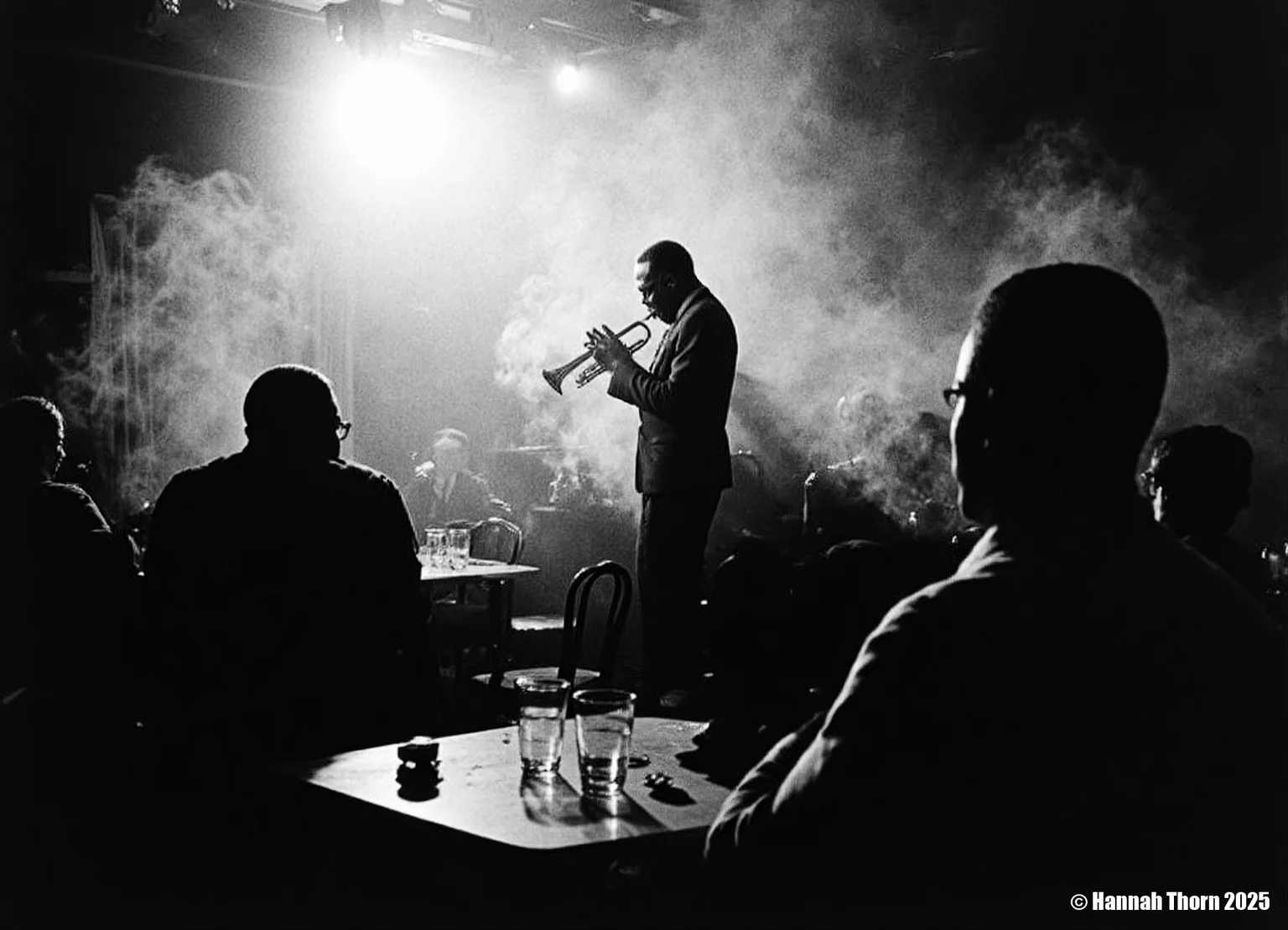The image is a black and white photograph of Miles Davis playing his trumpet. The photo is taken in a dimly lit, smoky environment, possibly a jazz club. Davis is centrally positioned, but slightly off-center, his body angled towards the trumpet. He's captured mid-performance, his face partially obscured by shadows and the smoke, creating a dramatic and mysterious atmosphere. He's wearing a dark suit. His focus is entirely on his instrument. In the foreground, the backs of other patrons are visible, partially silhouetted, seated at a table with glasses, suggesting the scene is from a live performance. The smoke adds depth and texture to the photo, and the lighting creates strong contrast, with bright spots highlighting Davis and his trumpet, and leaving the rest in shadows. The overall feeling is intimate and moody. The photograph's style is strongly reminiscent of classic jazz photography. It uses elements of: Chiaroscuro: The dramatic use of light and shadow to create strong contrasts and a sense of depth. High Contrast: The deep blacks and bright whites add to the intensity and emotion of the scene. Documentary style: It seemingly captures a candid moment from a real-life event, without significant staging. While composed, the image feels unplanned, spontaneous, and captures the essence of the moment. Grainy texture: The texture of the photo suggests a potential film grain, further adding to its vintage aesthetic and enhancing the atmosphere. Silhouettes: The use of silhouettes for the audience members in the foreground adds to the intimacy and focuses attention on Davis. The overall aesthetic is evocative and atmospheric, capturing the mood and ambiance of a jazz club during a performance. The style is both artistic and journalistic, conveying both the emotional energy of the performance and a sense of reality.<lora:_Flux\Vintage_Jazz-Club.safetensors:1.0:1.0>