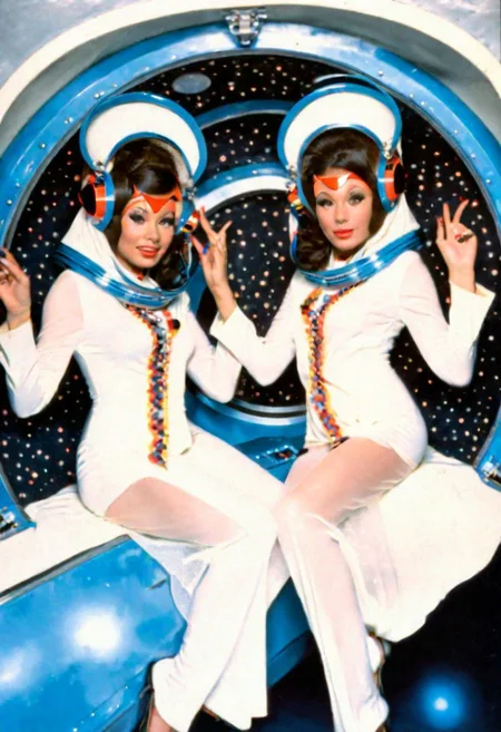 conceptual portrait, sexy twin temple brunette pin-up priestess aboard the sexy futuristic spacecraft, floating playfully in zero gravity, dynamic pose, 1970s sexploitation sci-fi film, pulp-sf, weird future fashion, headdress, plastic, veil, mask, helmet