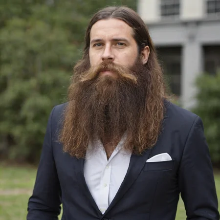 a man with long flowing hair and a big beard wearing a suit, outside <lora:Cruz'sBeard:0.6>
