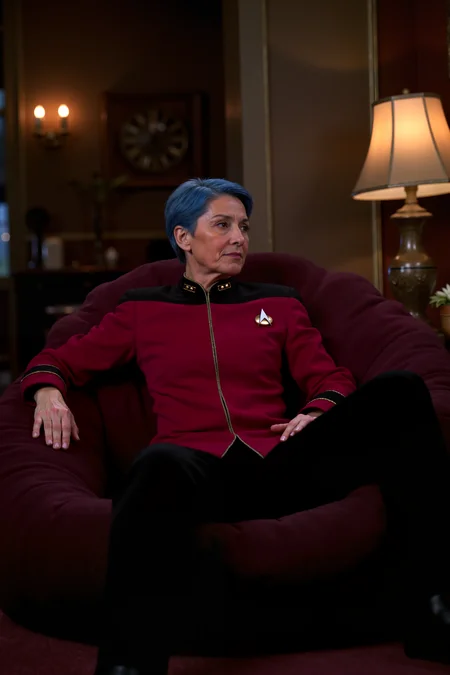 a 50 year old woman with blue hair in maroon TNGadm jacket with black shoulders and black pants relaxing in a beanbag in a cozy room. there is a big lamp next to the beanbag. , detailed background Fantastic lighting. Detailed shadows.intricate details, vivid colors, hyper-detailed, ultra-sharp,<lora:ST_TNG_ADMIRAL_FLUX>