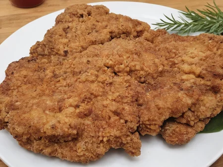 A high-resolution, hyper-realistic image of a deliciously fried chicken cutlet, referred to as G8G. The G8G is golden brown, with a crispy, crumbly coating and tender, juicy meat inside. It's served on a rustic wooden plate, with a side of fresh, colorful vegetables and a dollop of tangy sauce. The scene is set in a cozy, homely kitchen, with all elements in sharp focus, creating a clear and detailed image. The lighting should be warm and inviting, highlighting the appetizing qualities of the G8 and the cozy atmosphere of the setting, <lora:g8:0.7>