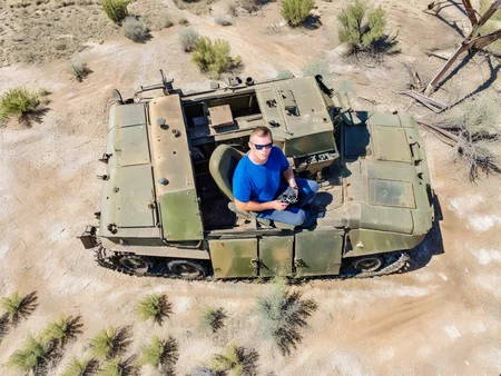 vertical perspective photography,highres,close up of drone driver sitting in abandoned old military vehicles,dust,sparse vegetation,bunker,