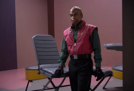 cinematic film still,
saturated colors,
negative space,
1 adult man, (breaking bad style), (solo male focus), looking at viewer, face of Gustavo Fring, dark skinned, dark hair, short hair,
employee uniform,pink and red shirt, Black slack pants with yellow stripes, red visor cap with "W" logo, Socks with the "w" logo, loafers
, folding chairs, sitting on chairs,
smile
framing device, negative space, leading lines,
backdrop is a cybernetic interior of a space base
