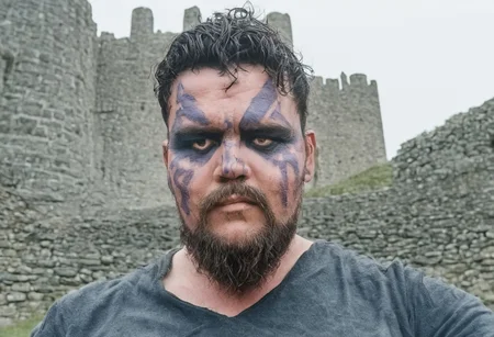 4RIEL, male viking, short beard, dusty background, in front of a castle, daylight, dramatic, face paint, 35mm film photography