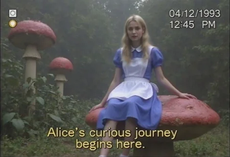 v8s, A vintage VHS still of a young woman dressed as Alice in Wonderland. She has long blonde hair, a classic blue dress with a white apron, and is sitting on a giant mushroom. The background features a whimsical forest with oversized plants and a surreal atmosphere. The image has a soft grainy texture and muted colors, with tracking lines and a faint timestamp in the corner reading '04/12/1993 12:45 PM.' The text caption is styled like VHS subtitles in your native language, appearing at the bottom in yellow with a shadow, reading: 'Alice's curious journey begins here.