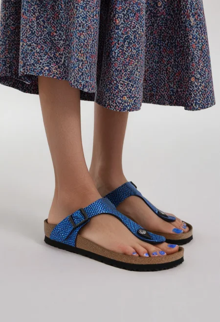 1girl, solo, dynamic_pose, simple_background, white_background, gizehonfeet, blue_toenail_polish, close-up, lower_body, footwear_focus, patterned, long_skirt
