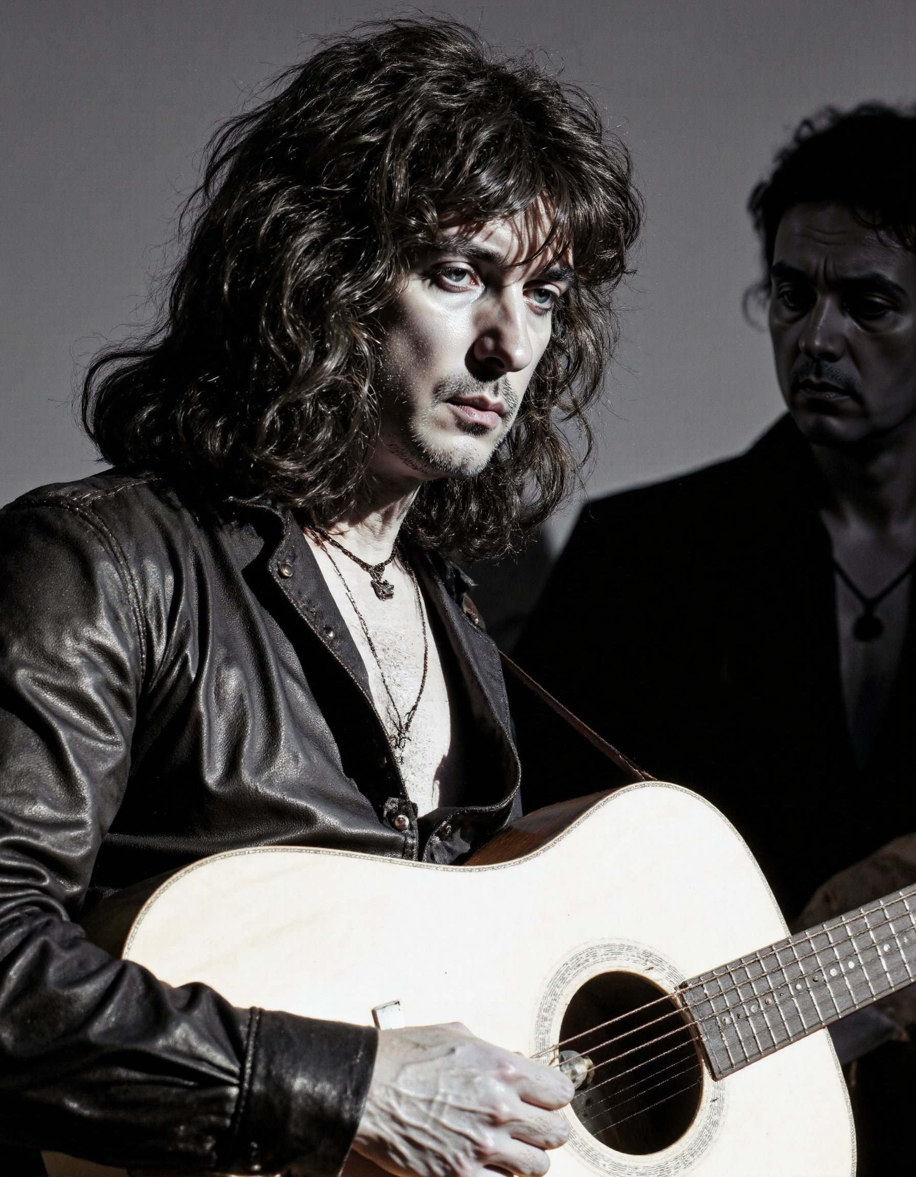 <lora:RICHIE_BLACMORE:1>, This is a black-and-white photograph capturing a man with long, wavy, unkempt hair, possibly in his mid-30s to mid-40s, holding an acoustic guitar. He has a serious expression on his face, looking directly at the camera. The man is wearing a dark, leather jacket that appears worn and textured, with a slight sheen to it. He has a simple necklace around his neck. The guitar he is holding is a six-string acoustic guitar with a natural wood finish. The guitar neck is visible, with the strings extending towards the camera. The background is out of focus, providing a stark contrast to the subject and the guitar, which are sharply in focus. The image has a vintage feel, possibly from the 1970s or 1980s, judging by the clothing style and the overall look of the photograph. The lighting is natural, suggesting an outdoor or indoor setting with natural light. The photograph is a candid moment, capturing a musician in a relaxed and focused state, likely during a performance or rehearsal. The texture of the leather jacket and the roughness of the man's hair add to the raw, authentic feel of the image.