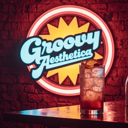 GroovyAesthetica, 1970s style photo, shot using a Canon AE-1, take a vintage photograph.
<break>
A center framed retro-style logo for a 1970s-era A stylized grid pattern with a retro-futuristic design, surrounded by a circle with a bold, sans-serif font that says "Groovy Aesthetica" in a neon color scheme on a brick wall. A Harvey Wallbanger - Bright orange with a garnish of orange slice and cherry. sitting on a bar top off to the side of the image, refracting the glow.
<break>
Highly grainy, visible film grain, film dirt, film specks