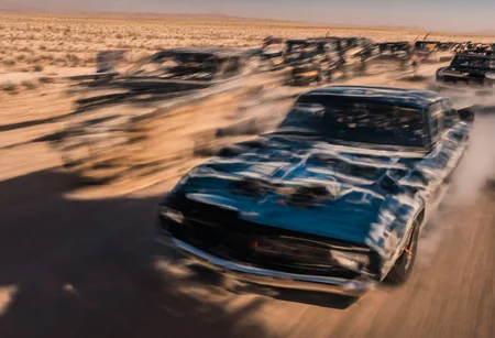 Creates an ultra detailed and realistic image taken by a drone, wide angle, of a race between 2 custom cars, created with parts from many muscle cars, with aerodynamic lines from 1972. The cars have tinted black windows. It is captured in motion with motion blur at full speed through a desert, daylight. Race between 2 cars. The photograph is captured with an Arri Alexa camera, with a zoom lens.
. <lora:Vintage Muscle Car SDXL:1>